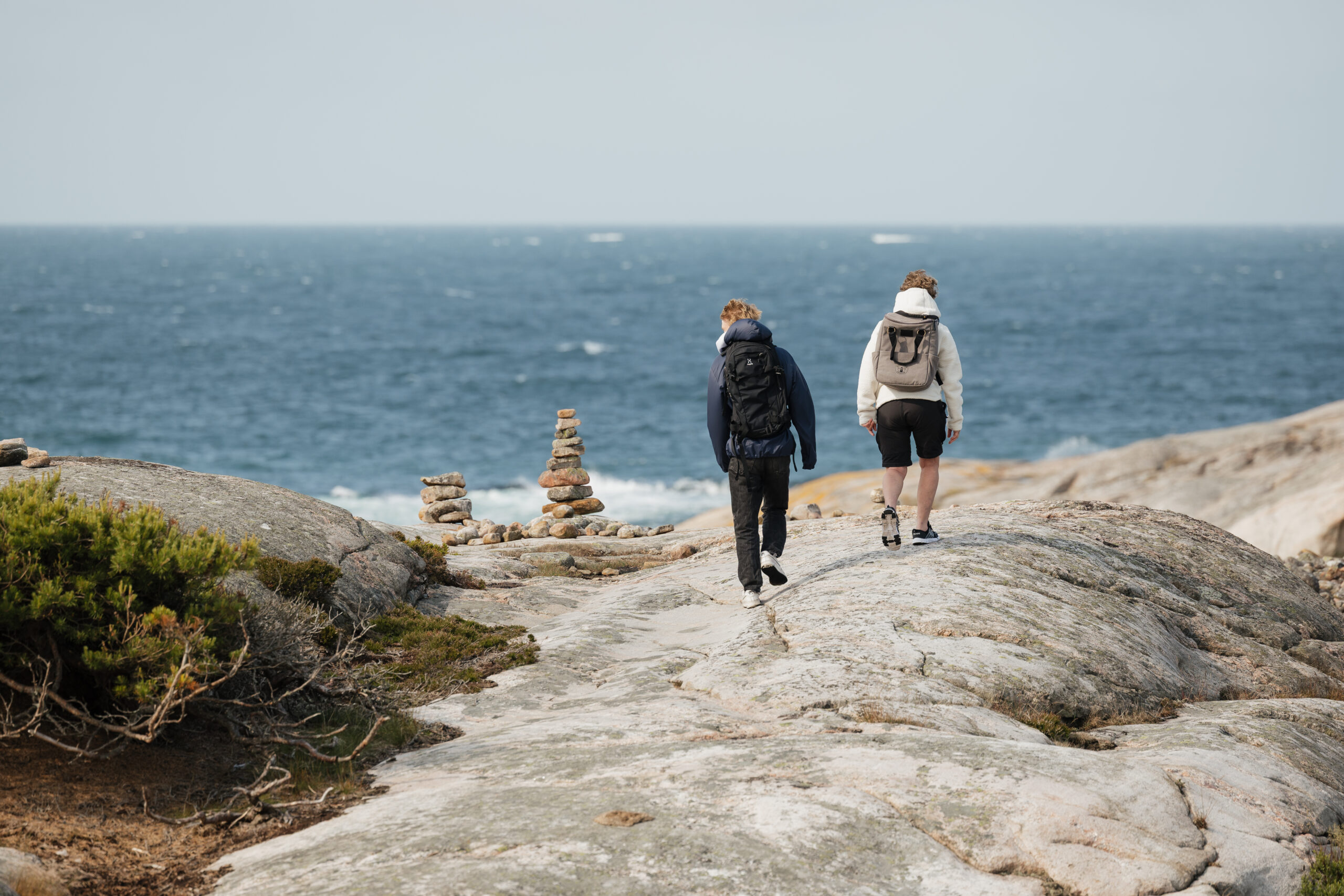 Två killar går på klippor vid vattnet